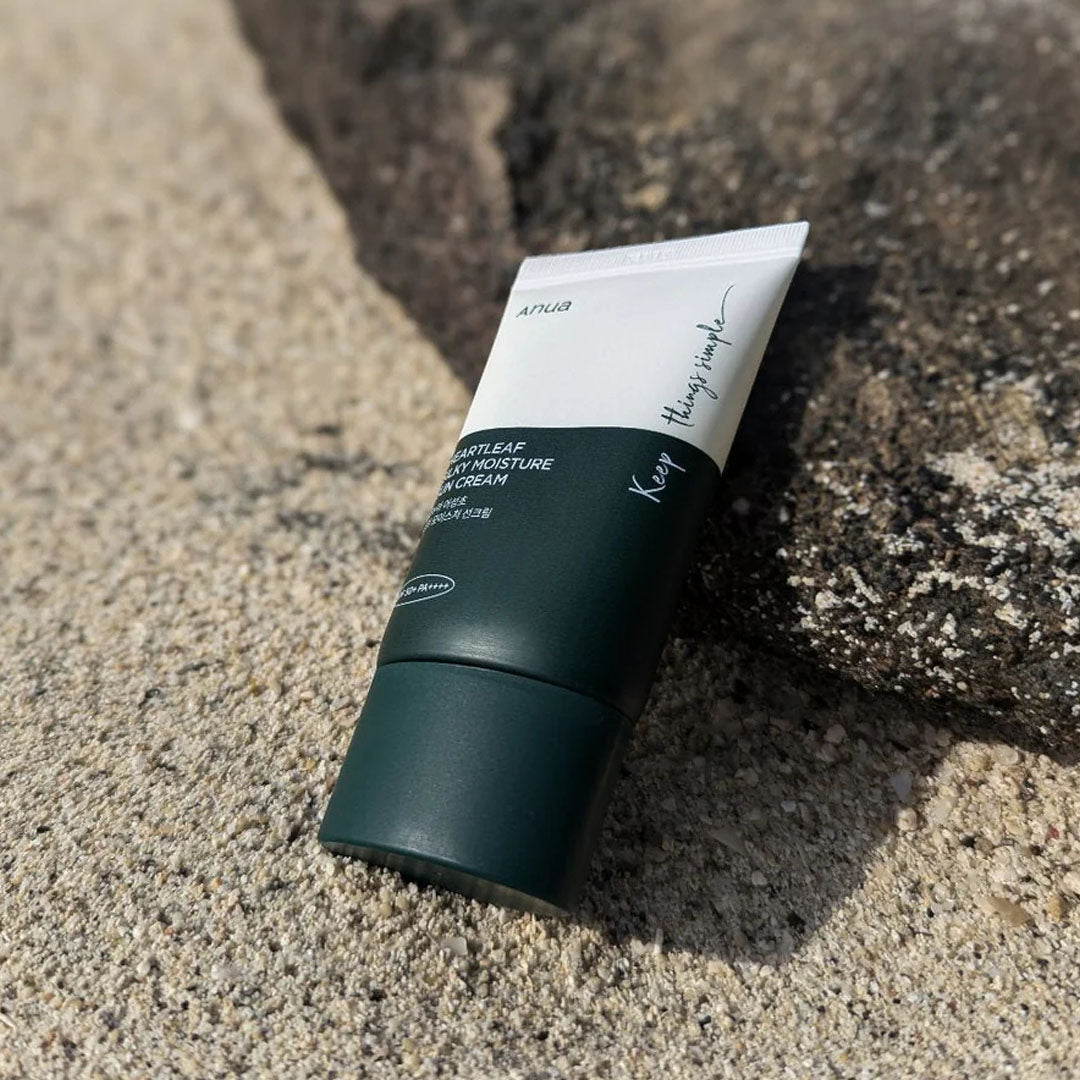 Anua Heartleaf Silky Moisture Sun Cream tube bottle on sand